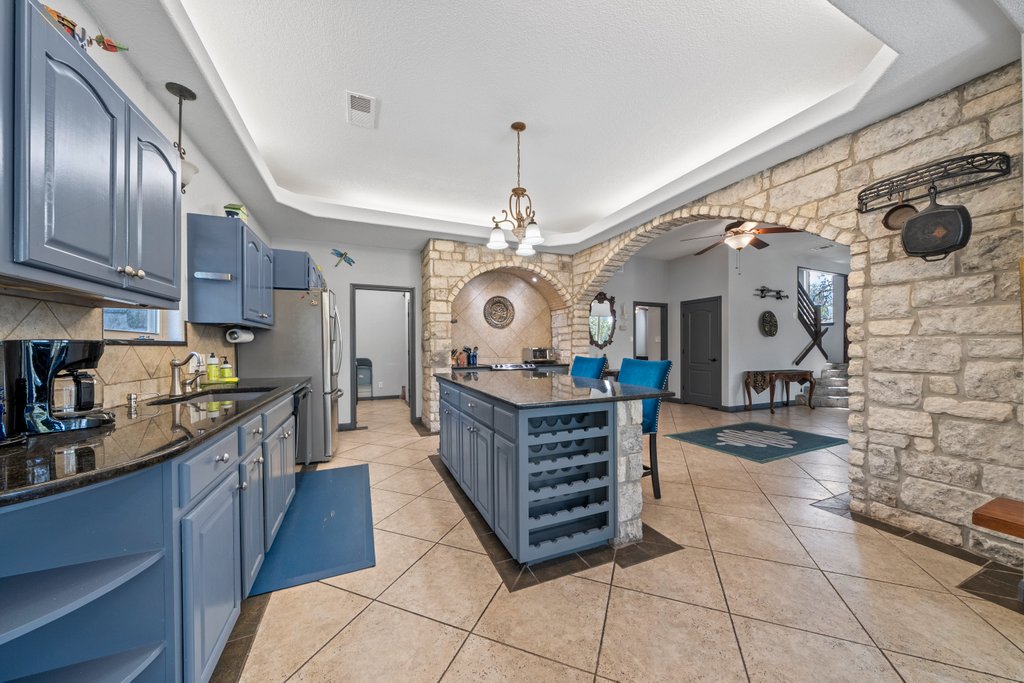 209 Lakeview Circle Spring Branch, TX 78070 - Photo 9 of 40 Kitchen with arched walkways, a tray ceiling, open shelves, a sink, and blue cabinets