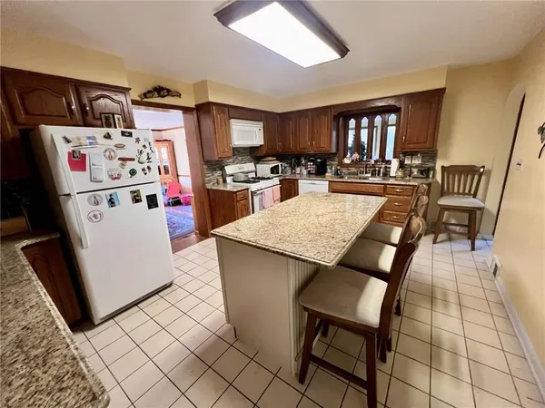 a kitchen with granite countertop a refrigerator a stove a sink dishwasher and a dining table with wooden floor