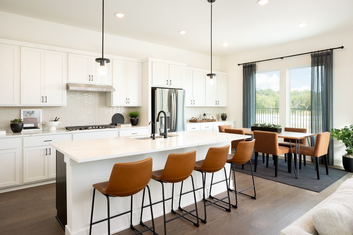 1407 Rambling Rose Road Austin, TX 78745 - Photo 3 of 12 a kitchen with stainless steel appliances granite countertop a stove a refrigerator a kitchen island a dining table and chairs