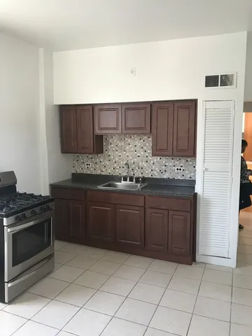 a kitchen with granite countertop a stove a sink and a microwave