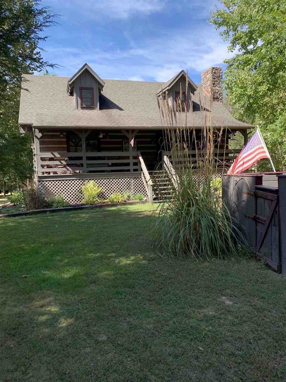 a front view of house with yard and trees in the background