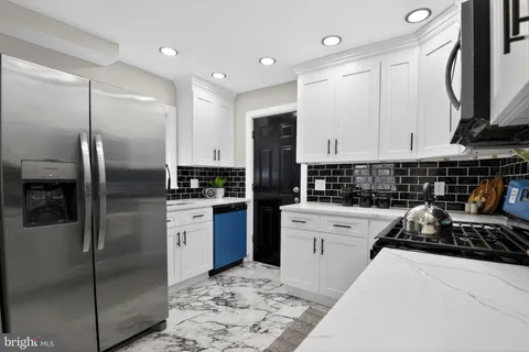 a kitchen with stainless steel appliances kitchen island granite countertop a refrigerator a sink a stove and white cabinets