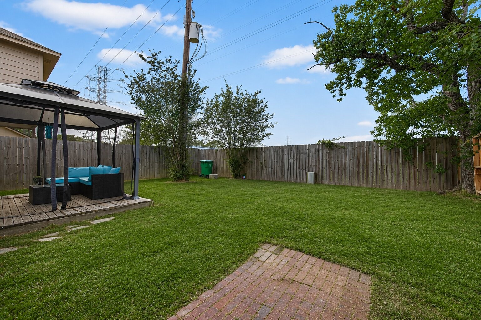 18446 North Willow Bluff Road Katy, TX 77449 - Photo 32 of 33 Spacious backyard with a lush lawn, featuring a wooden deck and gazebo ideal for relaxation. The area is fenced for privacy, with a few trees and shrubs adding greenery. Suitable for outdoor activities and entertaining.