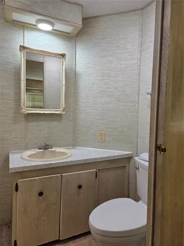 a bathroom with a toilet a sink a mirror and vanity