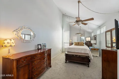 a spacious bedroom with a bed a chandelier and a dresser
