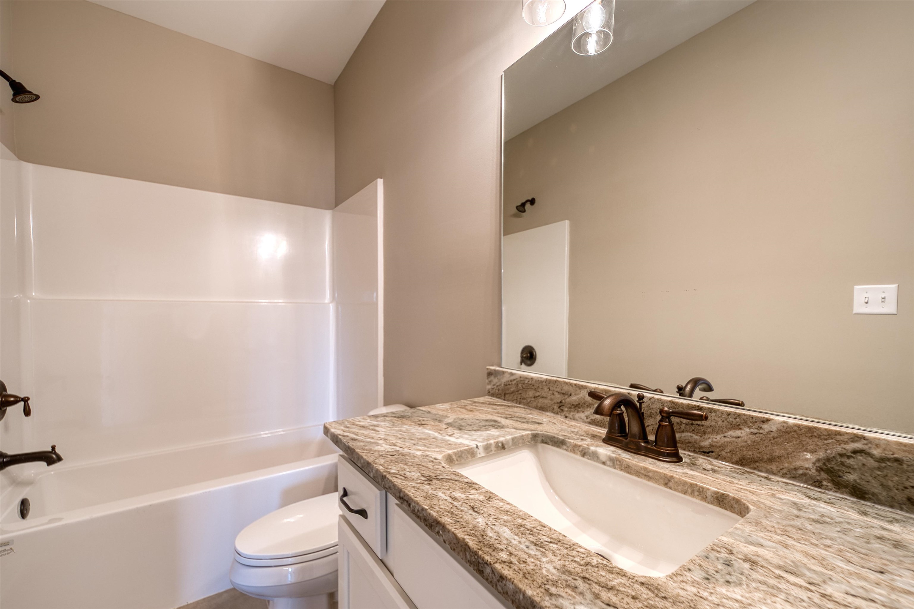 515 Garland Drive Covington, TN 38019 - Photo 32 of 38 a bathroom with a granite countertop sink a toilet and bathtub
