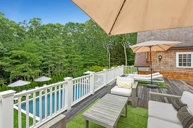 a view of a patio with couches table and chairs under an umbrella