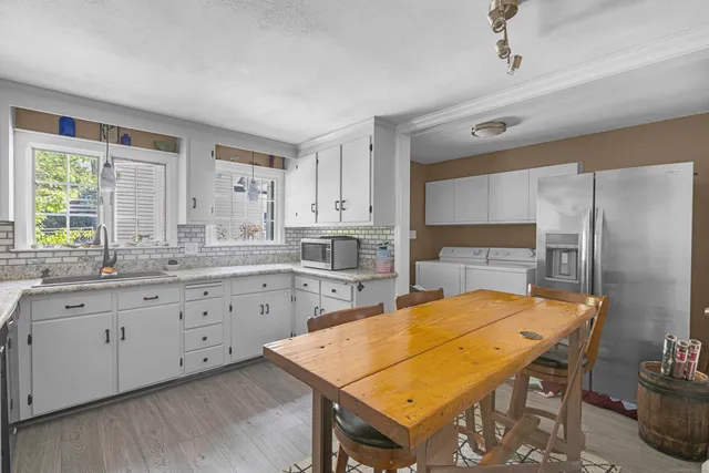 a kitchen with stainless steel appliances granite countertop a table chairs sink refrigerator and cabinets