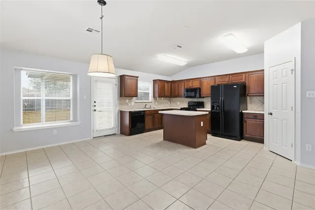 a kitchen with kitchen island granite countertop stainless steel appliances cabinets a sink and a window