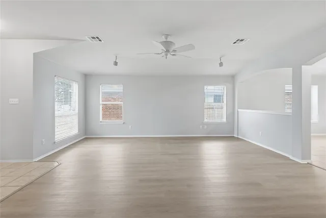 an empty room with wooden floor cabinet and windows