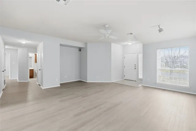 an empty room with wooden floor and windows