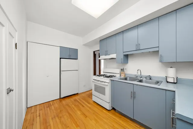 a kitchen with stainless steel appliances a sink cabinets and wooden floor