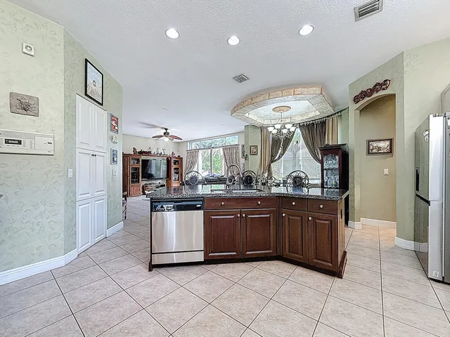 a utility room with stainless steel appliances granite countertop a sink and a window