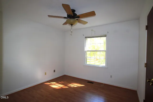 a view of empty room with window and ceiling fan