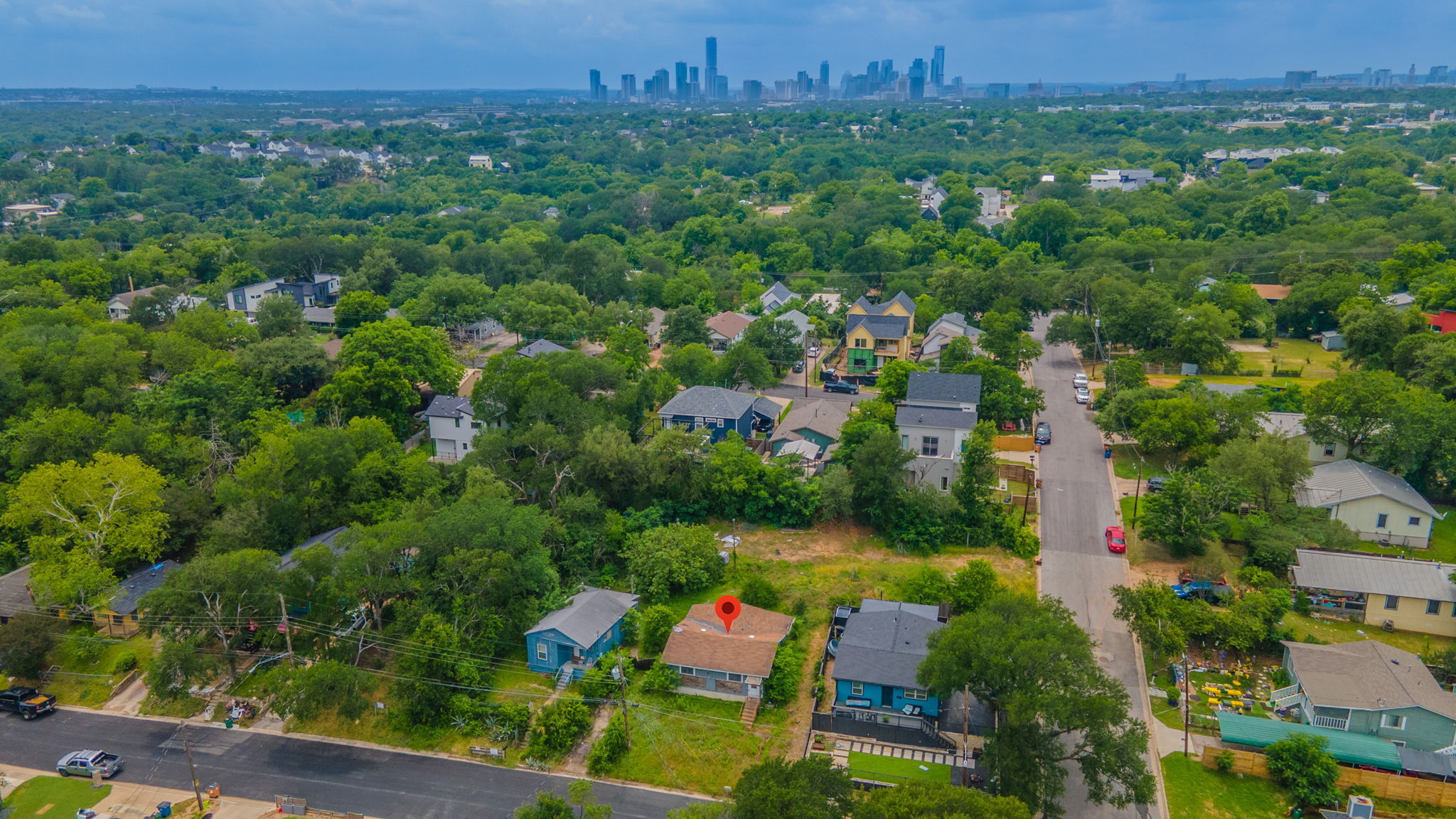 1410 Luna Street Austin, TX 78721 - Photo 4 of 5 An aerial panorama reveals a residential area nestled amongst mature trees with a distant city skyline.