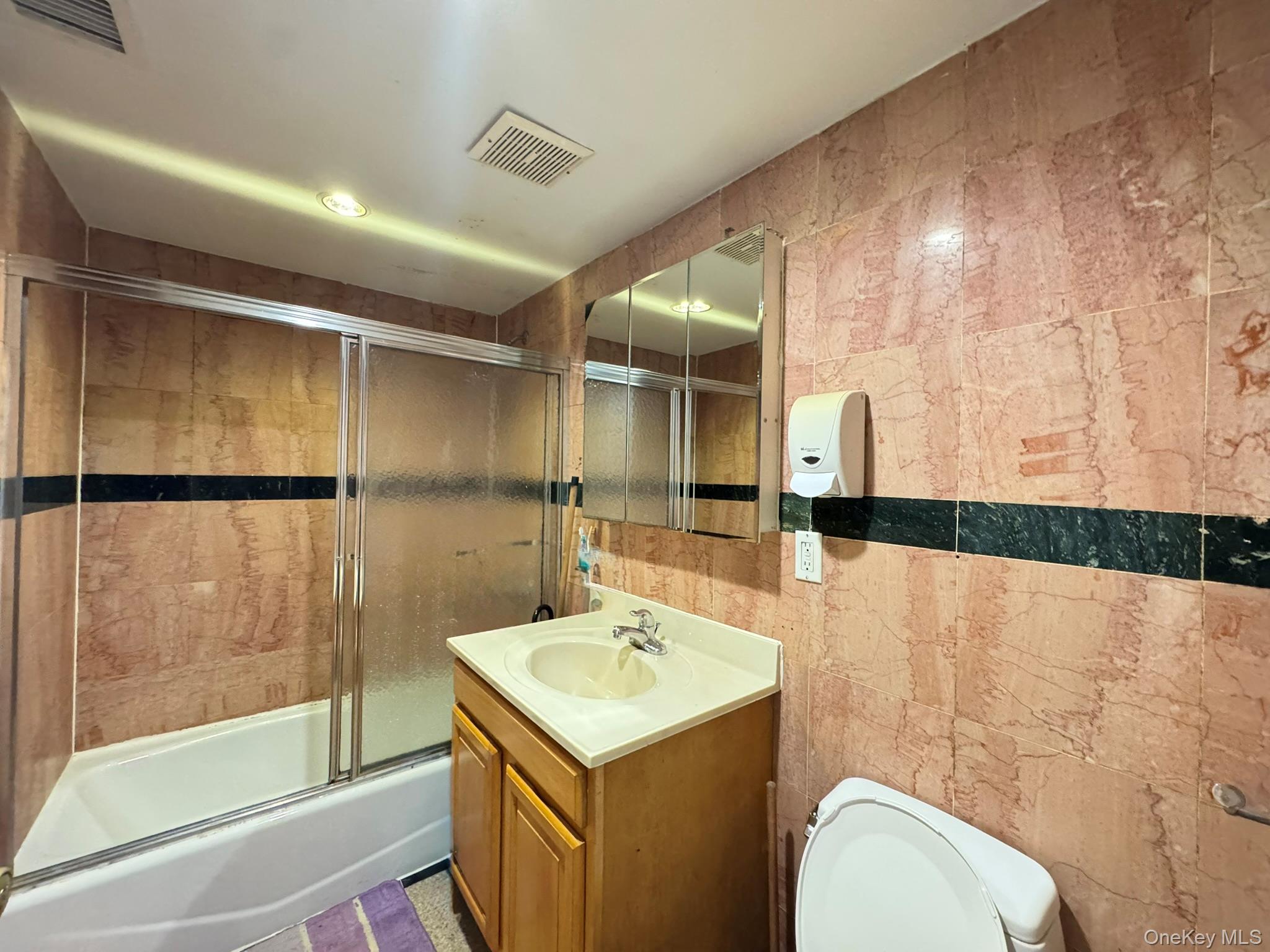 104-21 39th Avenue, Unit 211C Queens, NY 11368 - Photo 7 of 15 a bathroom with a sink and mirror with bathtub