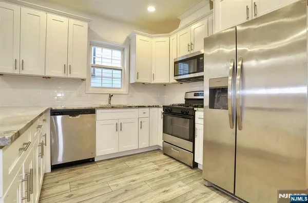 a kitchen with cabinets stainless steel appliances and a window