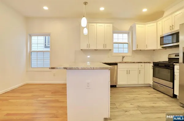 a kitchen with stainless steel appliances granite countertop a stove a sink and white cabinets