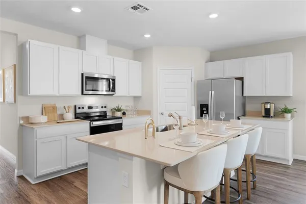 a kitchen with stainless steel appliances a sink a stove a table and chairs