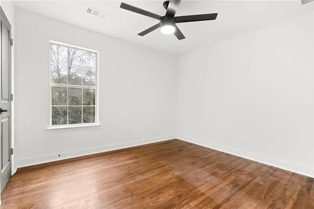 an empty room with wooden floor and natural light