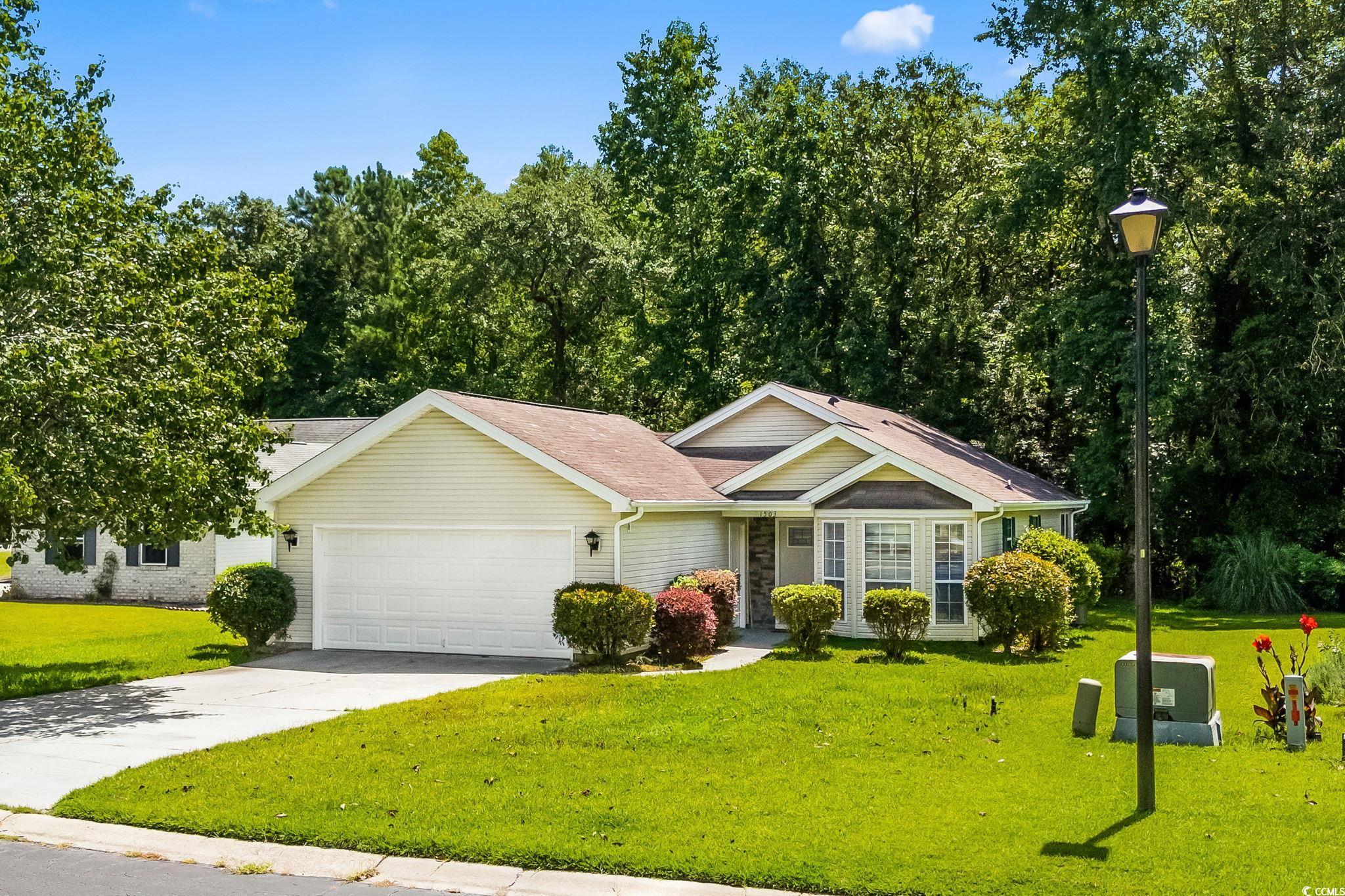 View of front of property with a garage, a front lawn, concrete driveway, and a shingled roof