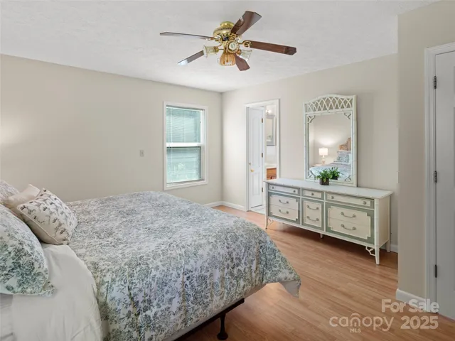 a bedroom with a bed a dresser and wooden floor