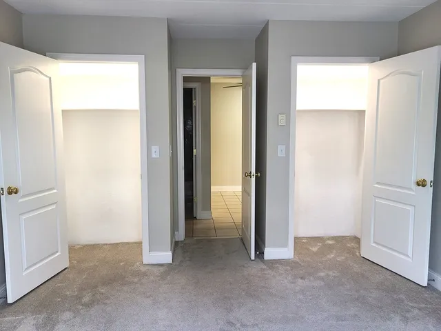 a view of an empty room with closet and a window