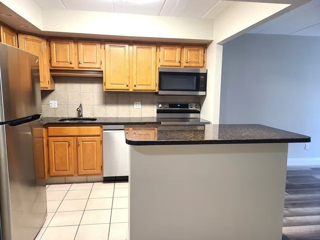 a kitchen with kitchen island granite countertop a sink appliances cabinets and a counter top space