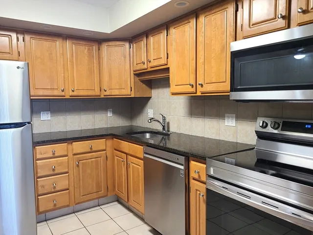 a kitchen with granite countertop cabinets stainless steel appliances and a sink