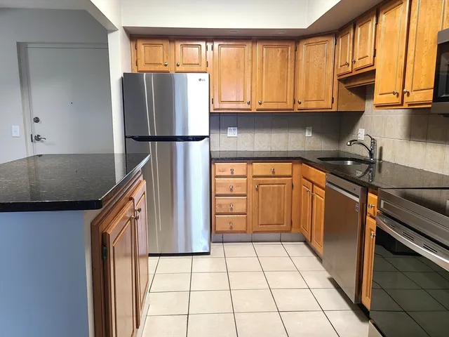 a kitchen with stainless steel appliances granite countertop a refrigerator a sink and a stove