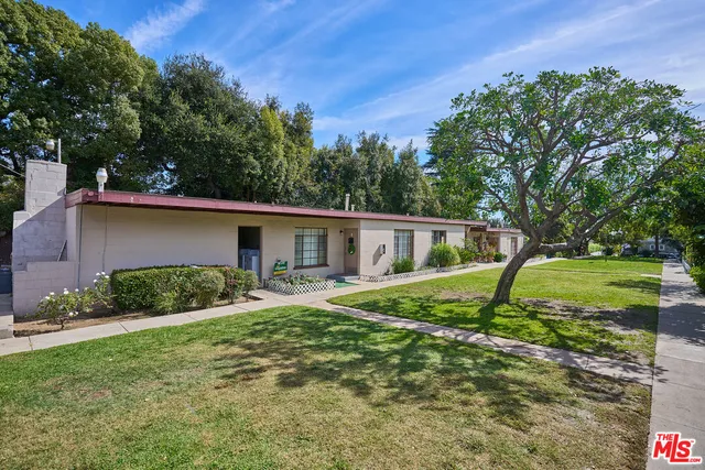 a view of a house with a yard and large tree