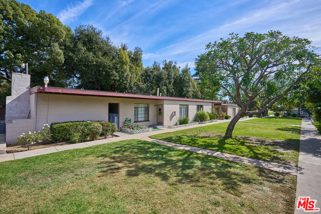a view of a house with a yard and large tree