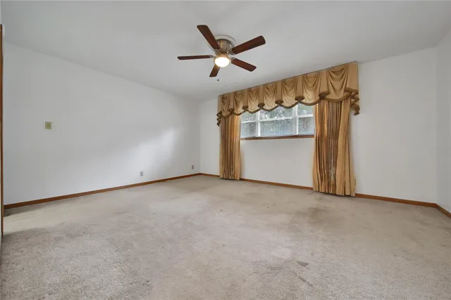 an empty room with a ceiling fan and windows