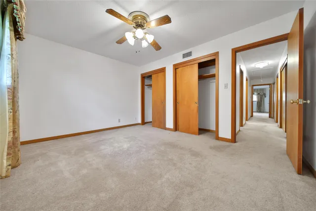 an empty room with a chandelier fan and windows