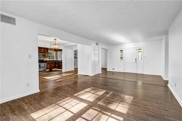 a view of empty room with wooden floor and kitchen