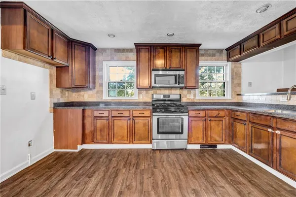 a kitchen with stainless steel appliances granite countertop a stove a sink dishwasher and a microwave oven with wooden floor