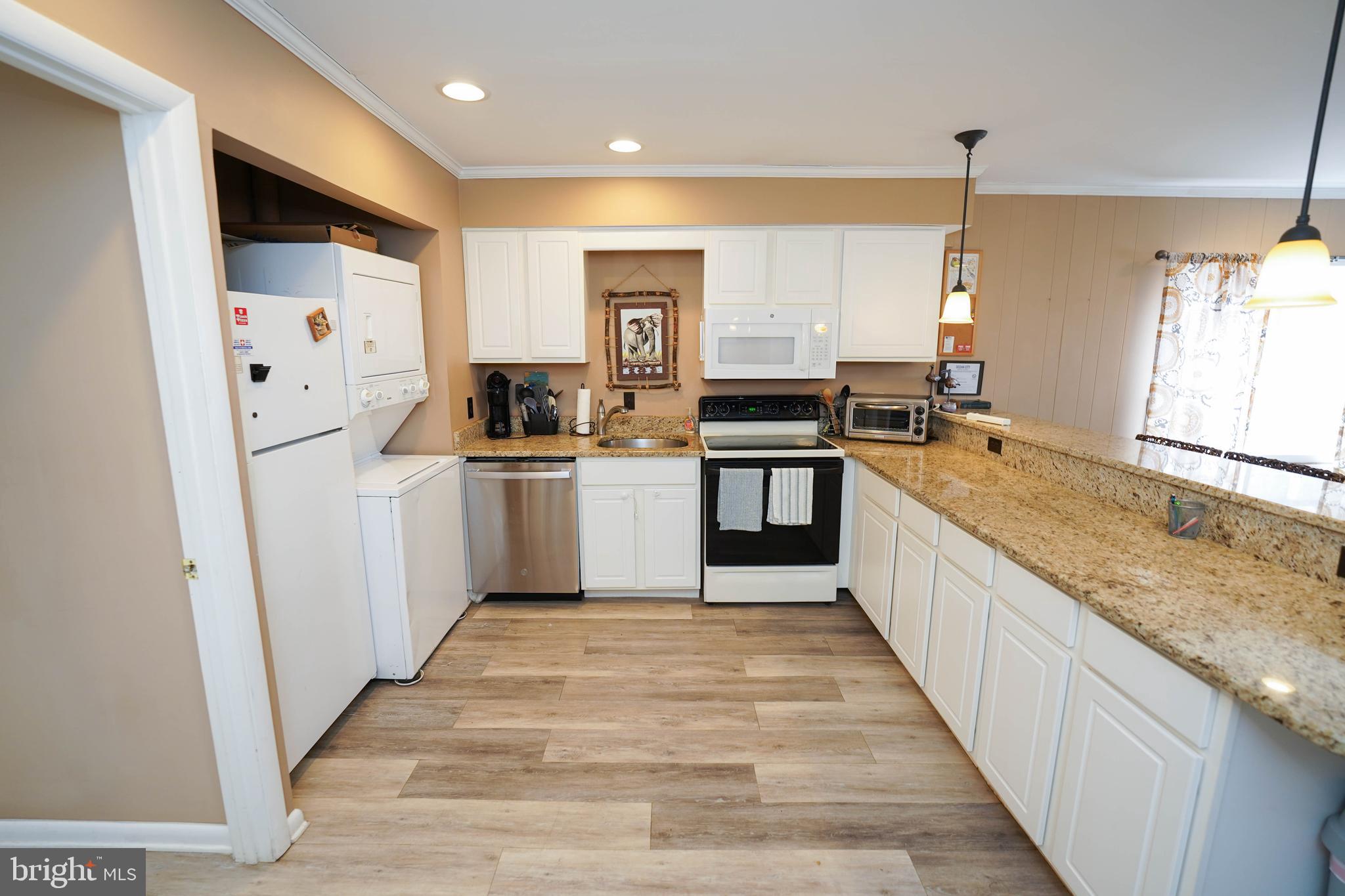 17 139th Street, Unit 101 Ocean City, MD 21842 - Photo 11 of 28 a large kitchen with stainless steel appliances granite countertop a refrigerator a sink and a stove