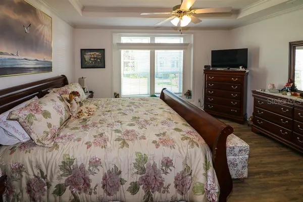 a bed sitting in a bedroom and a flat tv screen on dresser