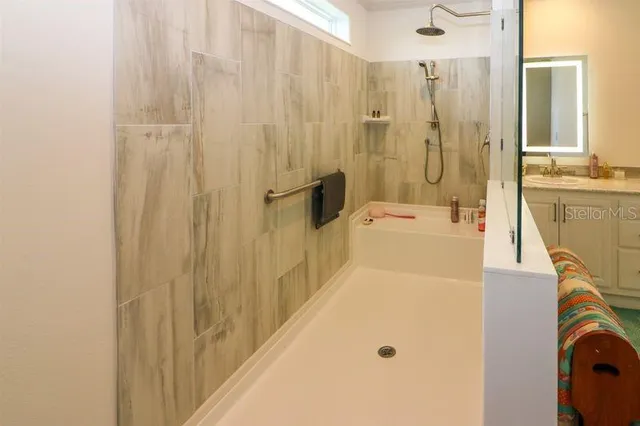 a bathroom with a tub a sink a mirror and a shower