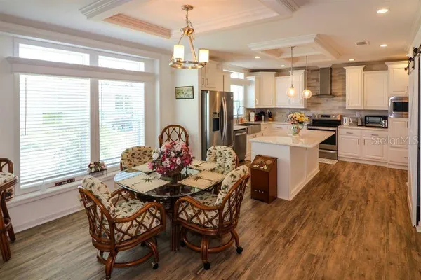 a living room with stainless steel appliances kitchen island granite countertop furniture a large window and wooden floor