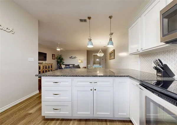 a kitchen with granite countertop a sink a stove and cabinets