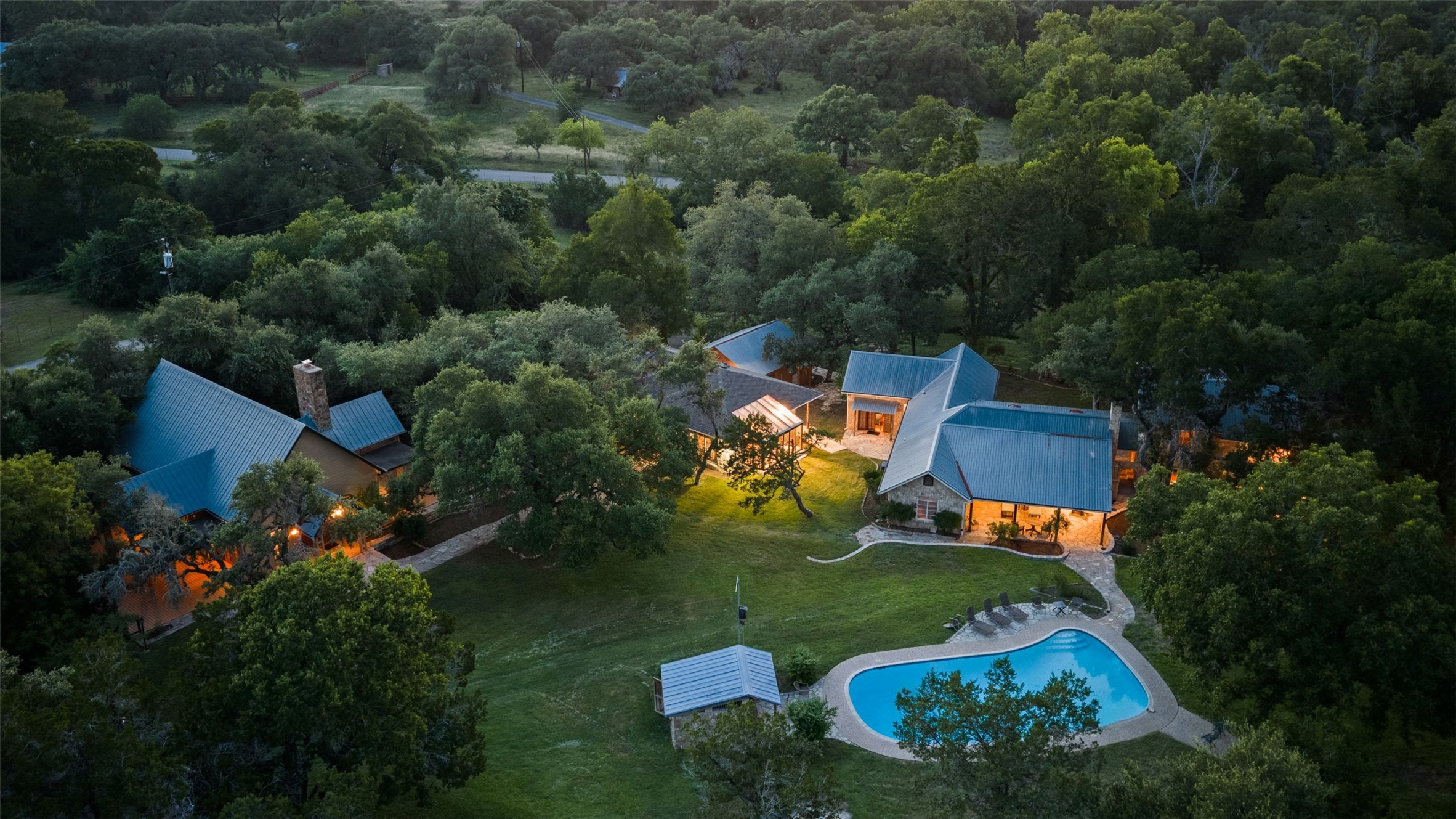 505 Red Corral Ranch Road Wimberley, TX 78676 - Photo 28 of 40 An aerial perspective reveals a private estate nestled within a lush, verdant landscape with a sparkling pool.