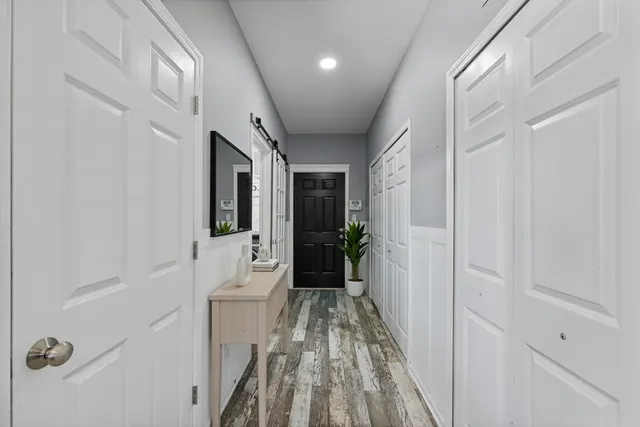 a hallway with white doors wooden floor and front door