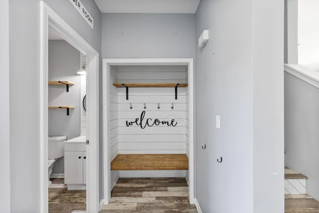 a view of a hallway with wooden floor and a bathroom