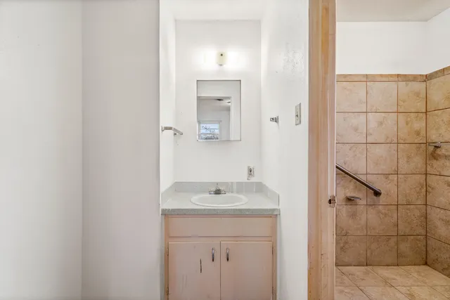 a bathroom with a granite countertop sink a mirror and shower