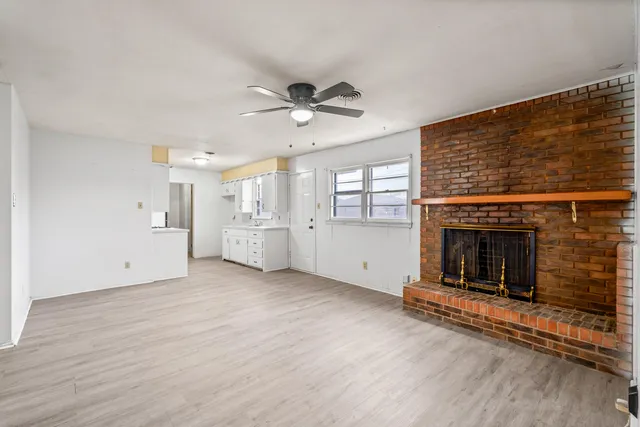 an empty room with windows and fireplace
