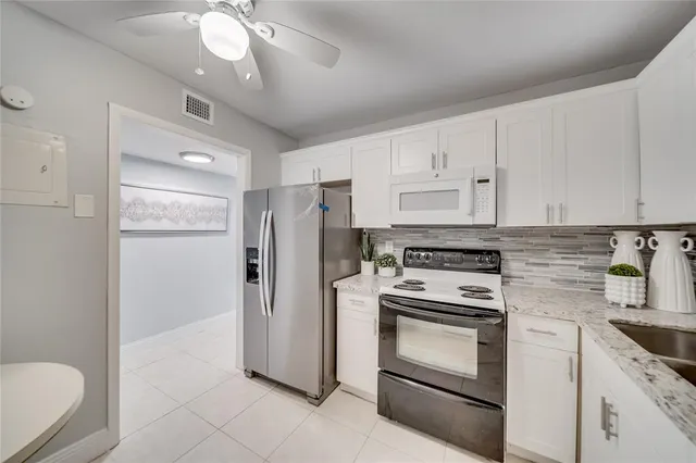 a kitchen with granite countertop white cabinets and white appliances