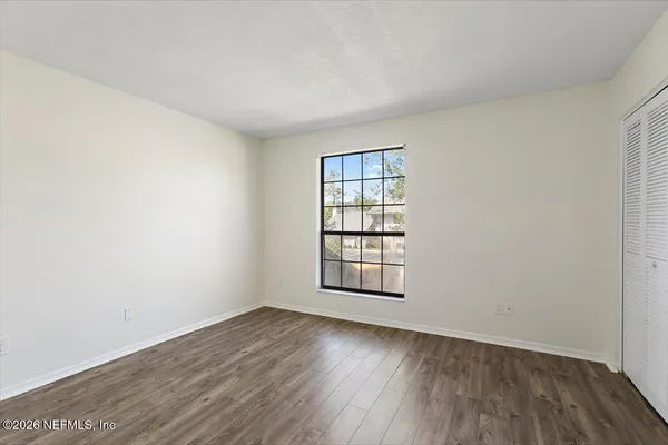 an empty room with wooden floor and windows