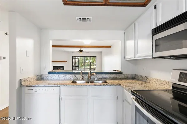 a kitchen with granite countertop a sink stainless steel appliances and cabinets
