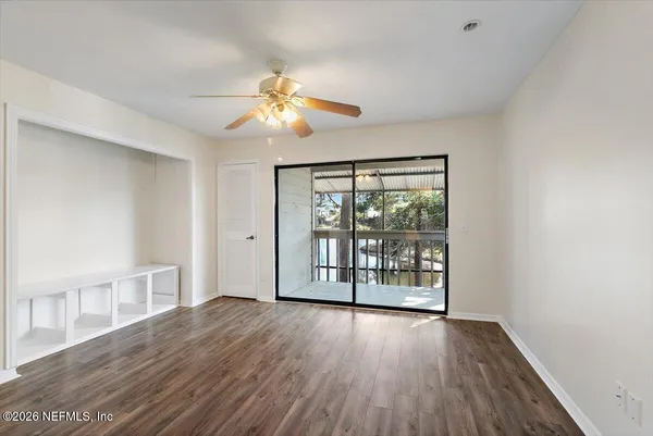 a view of an empty room with wooden floor and a window